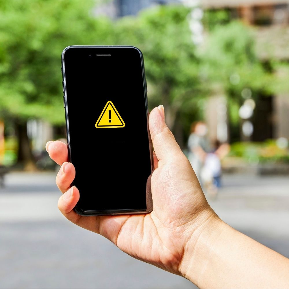Bild von einer Hand die ein Mobiltelefon hält. auf dem display ist ein warndreieck zu sehen, zur studie der info gmbh zum bundesweiten warntag
